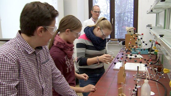 Mehrere Jungen und Mädchen, die die Goetheschule in Ilmenau besuchen, führen im Chemieunterricht Experimente durch
