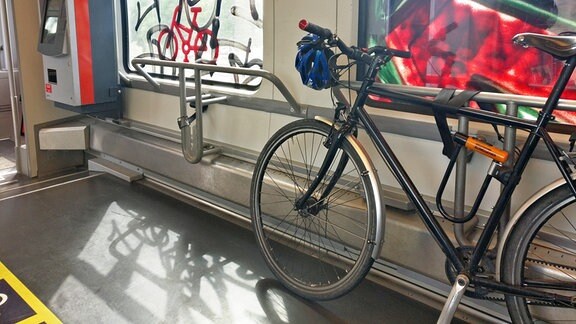 Ein Fahrrad lehnt in einem sonst leeren Zug am Fenster