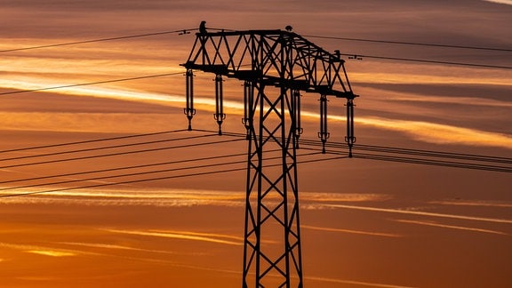 Ein Hochspannungsmast steht vor einem abendlichen Himmel.