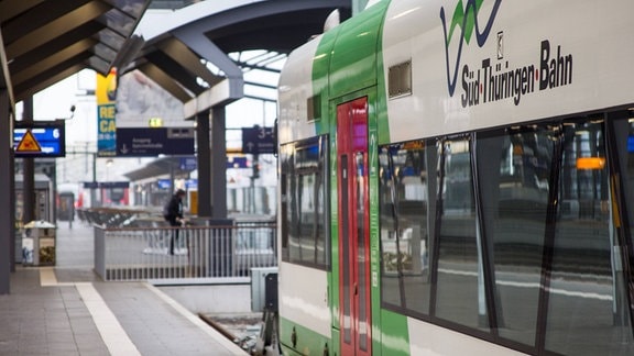 Seitenansicht einer Regional Bahn die an einem Bahnhof steht.