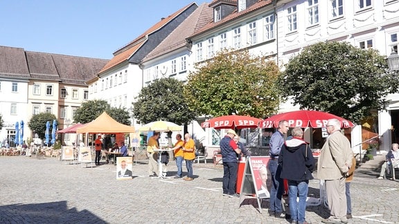 Wahlkampfstände verschiedener Parteien auf dem Marktplatz einer Innenstadt.