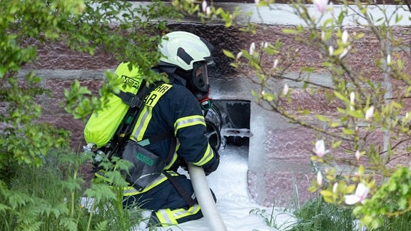 Ein Feuerwehrmann löscht durch ein Kellerfenster einen Brand in der Gaststätte "Goldener Löwe" in Kloster Veßra