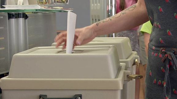 Eine Wählerin wirft ihren Wahlzettel in eine Wahlurne.