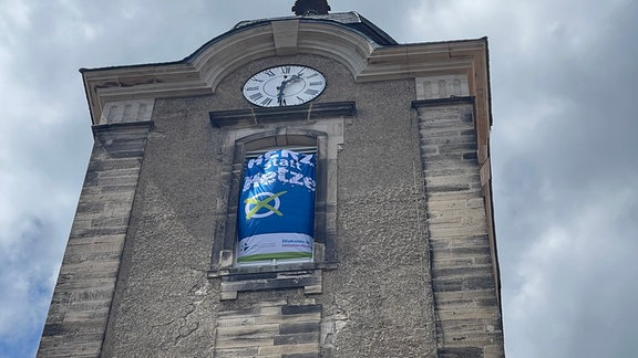 Ein Banner mit der Aufschrift "Herz statt Hetze" hängt am Glockenturm der Christuskirche in Hildbugrhausen.