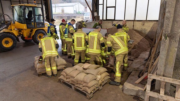 Feuerwehrleute stapeln Sandsäcke.