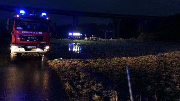 Ein Feurwehrauto steht bei Nacht auf einer Wiese.