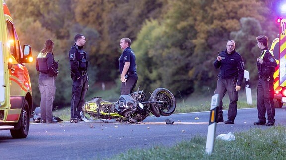 Fünf Polizisten stehen neben einem liegenden Motorrad.