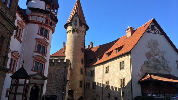 Blick auf eine Burganlage mit einem spitzen und einem runden Turm