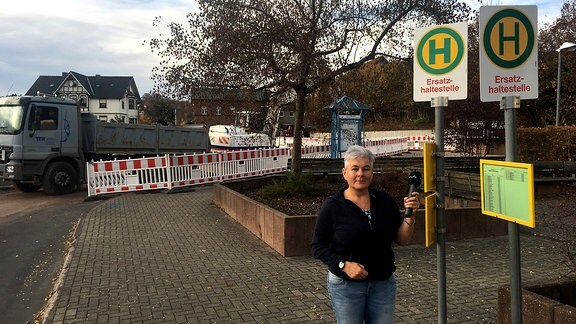 eine Frau steht vor einer Ersatzhaltestelle für Busse