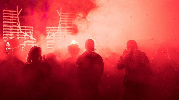 Rötliches Foto mit Menschen, die in Rauchschwaden stehen