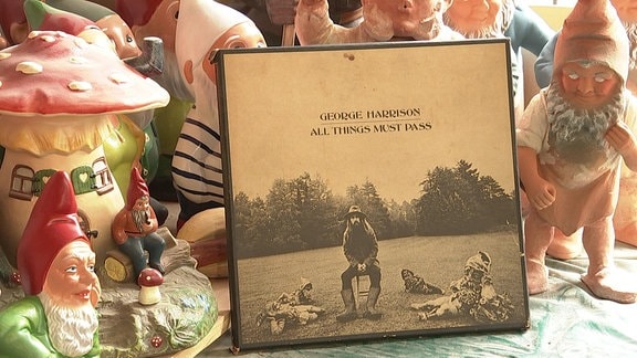 Eine Vinyl-LP "All things must pass" von George Harrison lehnt an Gartenzwergen.