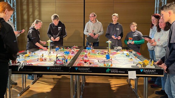 Teilnehmer um einem Tisch beim Roboterwettbewerb