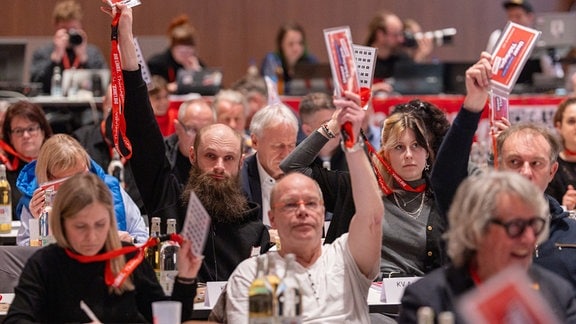 Delegierte stimmen bei einem Parteitag mit erhobenen Karten ab. 