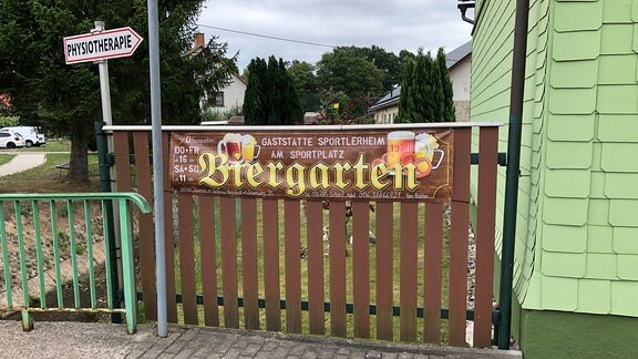 Ein Banner an einem Zaun weißt auf einen Biergarten hin. 