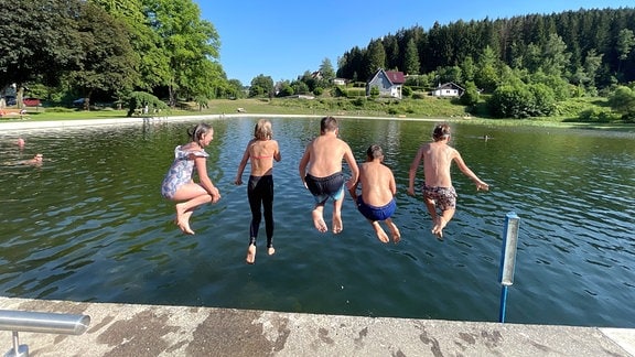Kinder springen in das Naturbad Stützerbach