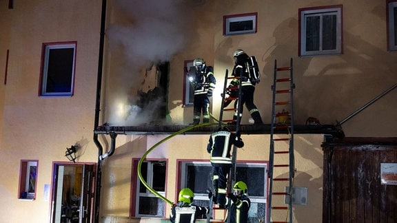 Feuerwehrleute löschen an einem Haus.