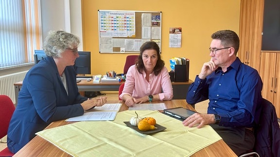 Drei Menschen sitzen an einem Tisch in einem Büro, die Direktroren der Regelschule gegenüber voneinander, die Schulamtsleiterin an der Stirnseite.