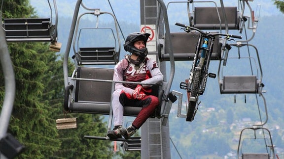 Mann sitzt mit einem Mountainbike auf einem Lift