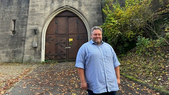 Fabian Giesder steht vor einem Tor von Schloss Landsberg. Auf dem Boden liegt Laub.