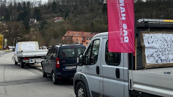 Fahrzeuge mit Protest-Schildern.