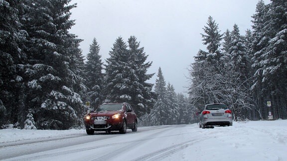 Zwei Autos auf einer schneebedeckten Straße.