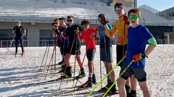 Jugendliche in kurzen Hosen, auf Ski - Trainingsgruppe des Sportgymnasiums im Biathlonstadion Ski-Langlauf