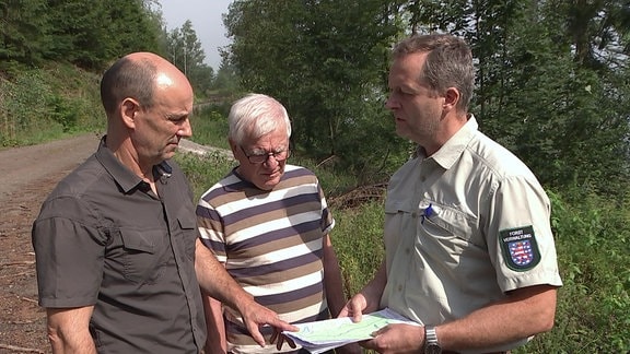 Drei Männer schauen auf eine Karte.