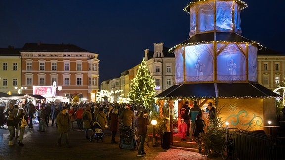 Menschen mit Mundschutz besuchen 2020 Stände auf dem weihnachtlich geschmückten Marktplatz von Meiningen