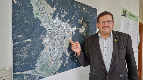 Uwe Scheler, Bürgermeister von Neuhaus am Rennweg zeigt auf eine Karte der Stadt