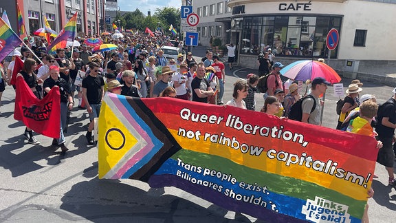 Menschen mit Regenbogenfahnen ziehen durch die Sonneberger Innenstadt