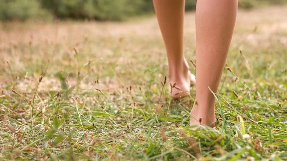 Eine junge Frau barfuß im Gras