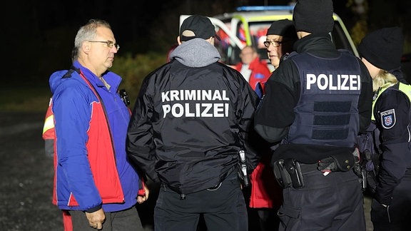 Mehrere Personen stehen zusammen. Auf dem Rücken einer Jacke steht groß Kriminalpolizei.