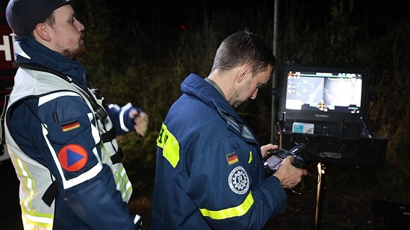 Mit Mitarbeiter des Technischen Hilfswerks. Einer bedient die Steuerung einer Drohne.