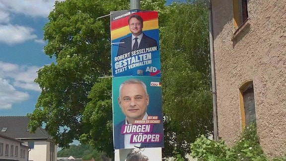 Zwei Wahplakate mit Jürgen Köpper und Robert Sesselmann hängen übereinander.