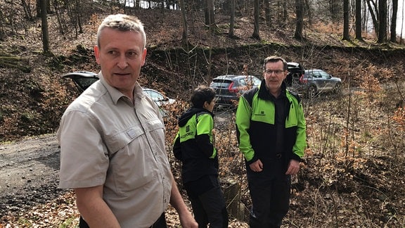 Ein Mann von Thüringenforst steht mit anderen Arbeitern im Wald