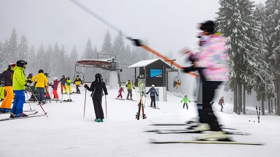 Skifahrer fahren auf dem Lift an der Bergstation der Skiarena Silbersattel.