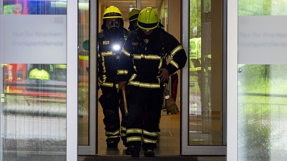 Feuerwehrleute gehen durch den Eingangsbereich einer Klinik.