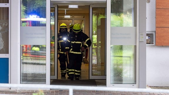 Feuerwehrleute gehen durch den Eingangsbereich einer Klinik.