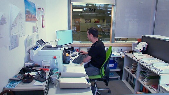 Ein Mann sitzt im Büro an einem PC