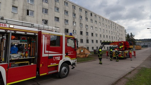 Feuerwehr vor einem hellen Gebäude (Plattenbau)