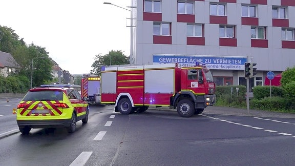 Feuerwehrautos stehen auf einer Kreuzung vor einem Hochhaus.