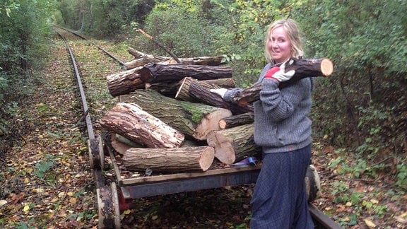 Eine Frau lädt Holz auf eine Bahn-Lore