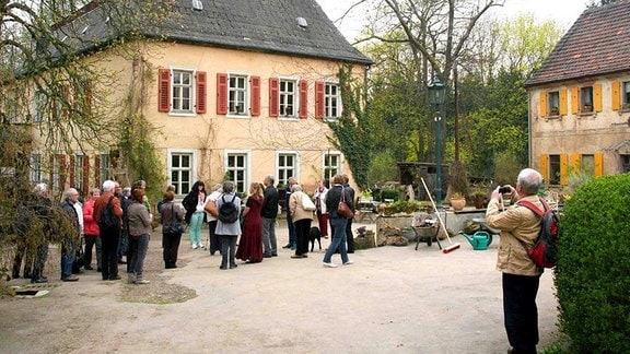 Eine Gruppe Menschen steht vor dem Herrenhaus und fotografiert