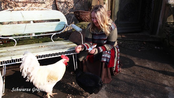 Eine Frau füttert ein Huhn