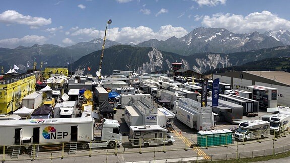 Dutzende Übertragungswagen und Wohnmobile, im Hintergrund die Alpen.