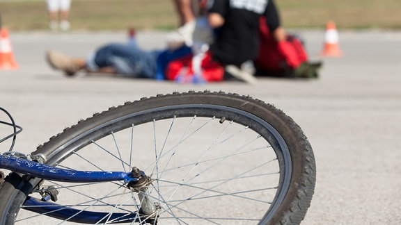 Fahrrad liegt am Boden, im Hintergrund wird ein Verletzter versorgt