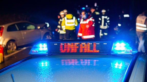 Ein Einsatzfahrzeug, der Polizei steht mit Blaulicht und dem Schriftzug Unfall im Display an einem Unfallort. 