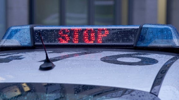 Der Schriftzug "Stop" ist neben dem Blaulicht auf dem Dach eines Polizeiautos zu lesen.
