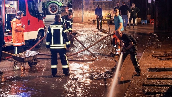 Feuerwehrmänner und Helfer bekämpfen eine Schlammlawine.