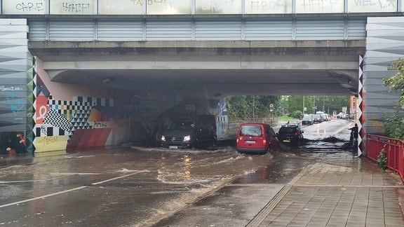 Autos fahren durch eine Unterführung, die überschwemmt ist